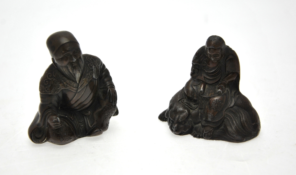 Two Chinese 'bronzed' figures, one seated on a mythical animal, approx. 6.5 cm h.