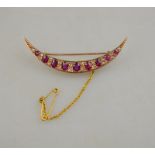 A ruby and diamond open crescent brooch set with nine graduated rubies and eighteen eight-cut and
