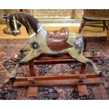 An antique wooden rocking horse, dappled painted finish, glass eyes, studded leather saddle,