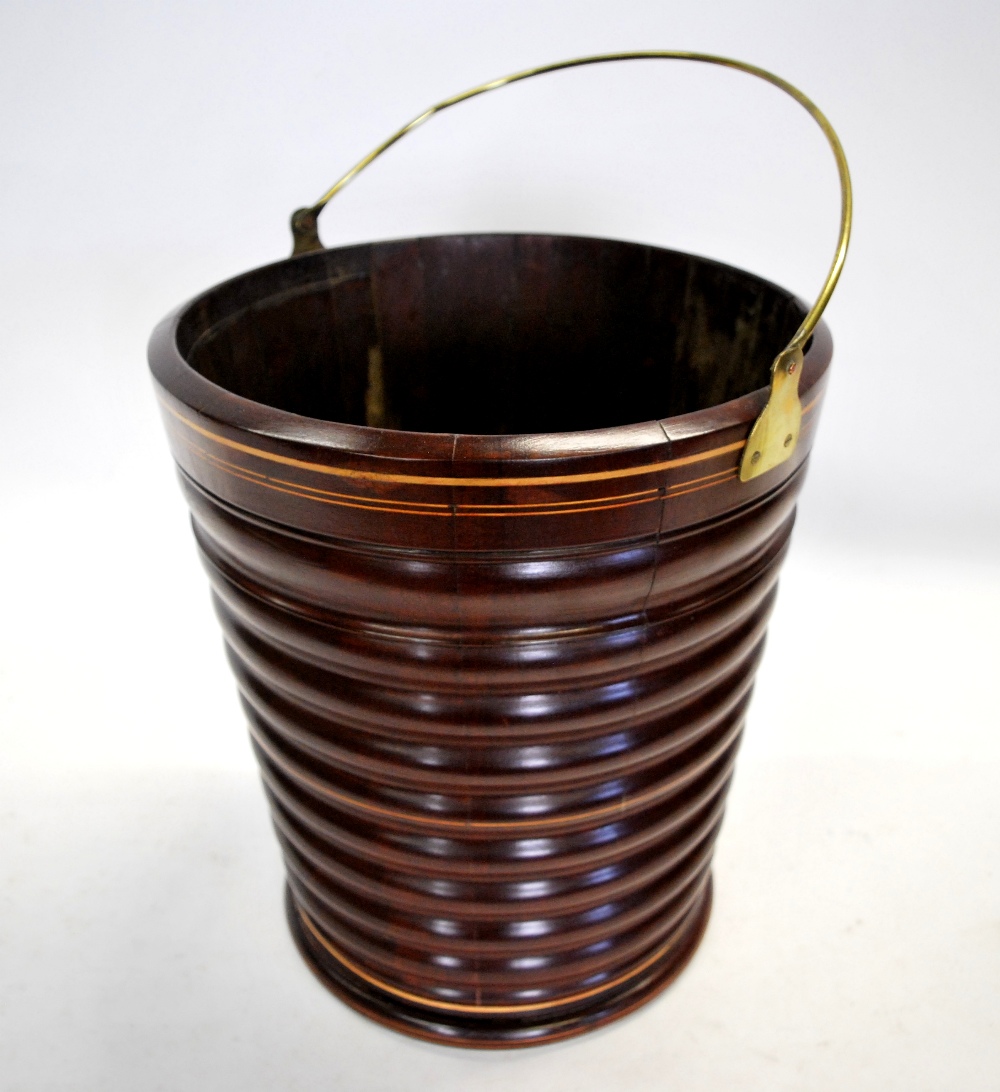 A mahogany peat bucket of ribbed and tapering form with stringing and brass loop handle,