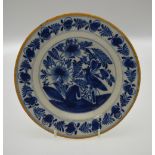 An 18th century English Delft blue and white plate decorated with a bird on a fence amidst flowers