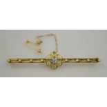 An unmarked yellow metal bar brooch, set with an aquamarine in foliate surround,