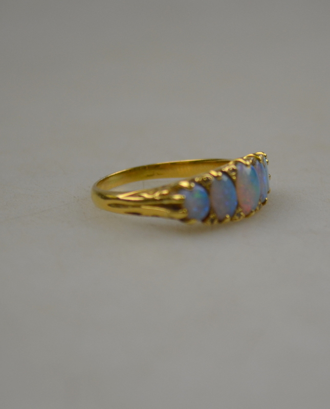 A black opal five stone ring with rose points between, 18ct yellow gold carved claw setting,