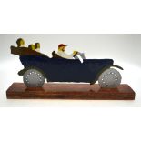 A cold-painted flame-cut sheet steel model car, on wood stand,