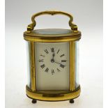 A lacquered brass ovoid cased carriage clock with folding carrying handle, 15 cm high overall