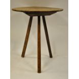 An antique elm cricket table, the circular top raised on three legs, 50 cm dia x 57 cm high