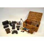 A selection of vintage cameras and binoculars in wicker hamper, including Deckel Compur 'Dolly',