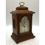 An oak cased eight day bracket clock with silvered arched dial,