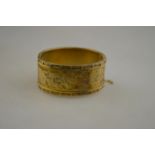 A Victorian gilt metal half engraved bangle, engraved in the centre 'Souvenir', with floral and