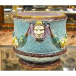 A large Minton style majolica jardiniere decorated in relief with three masks joined with floral and