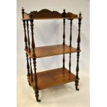 A Victorian three tier inlaid rosewood whatnot raised on short turned legs to brass castors