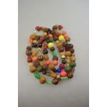 A long row of Oriental multi-coloured carved, polished and faceted beads including jade, bone,