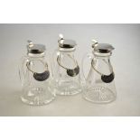 A set of three conical glass whisky drams with star-cut bases and silver collars and covers,