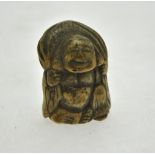 A Japanese bone netsuki carved as Hotei carrying his lucky bag, 4 cm h.