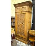 A late 19th century oak hall cupboard having a lunette centred cornice over a relief carved