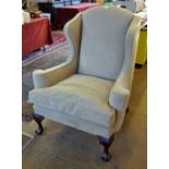 A contemporary Georgian style wingback armchair upholstered in mid-tan suede,