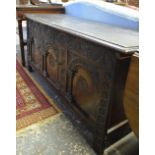 A 17th century oak coffer, the wide two plank hinged top over an elaborate lunette carved frieze and