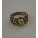 A Carol Darby moonstone ring, silver set with applied scrollwork and gilt highlights,