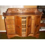 Victorian oak cabinet with double door cupboard flanked by cupboards concealing four drawers.
