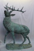 A 20th century bronze model of a stag, with head raised roaring with foot raised on an oval base,