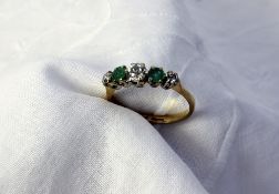 An emerald and diamond ring set with thr