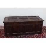 An 18th century oak coffer, the rectangular top with six carved panels, the front with panels on