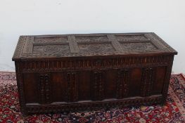 An 18th century oak coffer, the rectangular top with six carved panels, the front with panels on