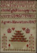 A mid 19th century sampler with the alphabet to the top, a vase of flowers, crowns and hearts, "