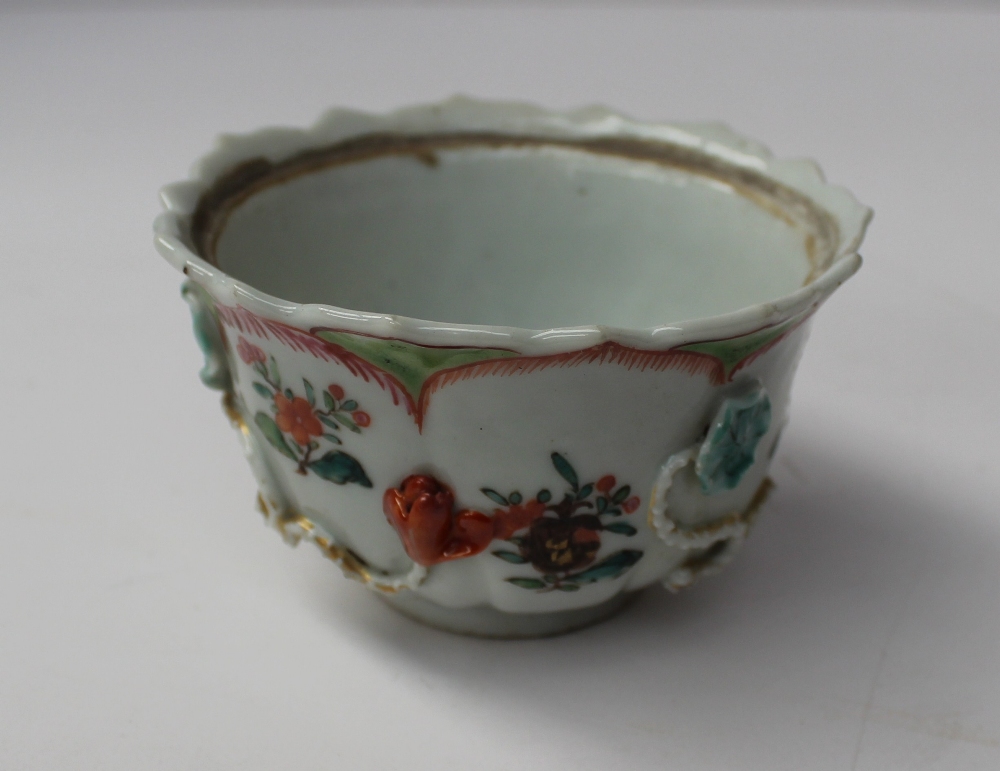 A 19th century Chinese porcelain bowl with a scalloped edge with ogee panels, sprays of garden