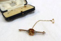 A bar brooch set with a central rectangular citrine, flanked by old cut diamonds to a yellow and