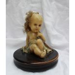 A wax model of a small child seated with