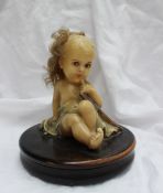A wax model of a small child seated with
