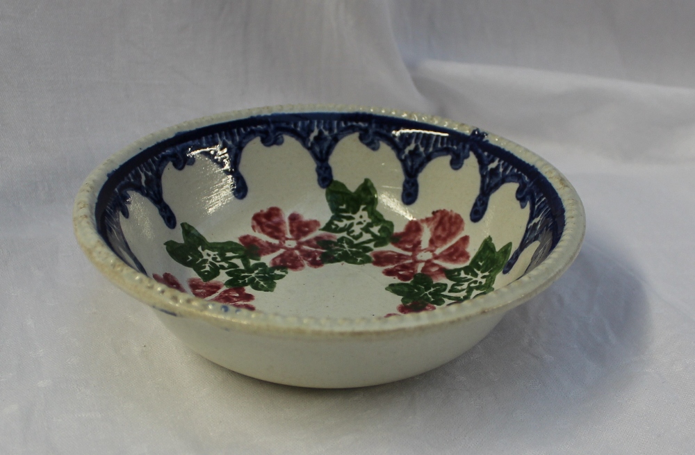 A 19th century spongeware bowl decorated with flowerheads and leaves to a blue swag drop border,