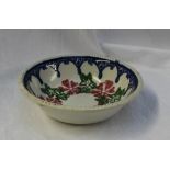 A 19th century spongeware bowl decorated with flowerheads and leaves to a blue swag drop border,