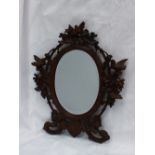 A black forest carved wall mirror, the surmount with a bird amongst leaves, with birds to the