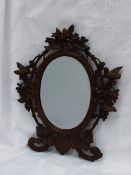 A black forest carved wall mirror, the surmount with a bird amongst leaves, with birds to the