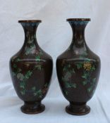 A pair of Japanese cloisonne enamel vases decorated with floral sprigs and scrolls to a black