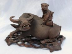 A carved Chinese hardwood figure depicting a boy seated astride a Water buffalo,