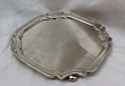A George V silver salver of square form with shaped corners on flattened bun feet, Sheffield, 1933,