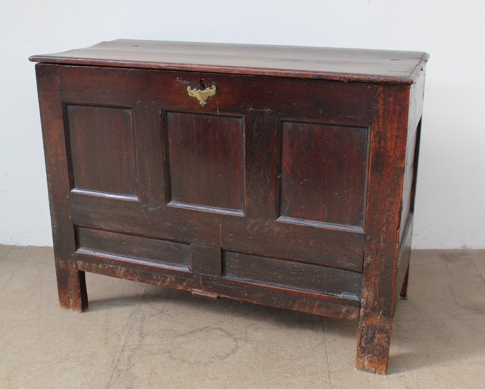 An 18th century oak coffer, the planked rectangular top above a four panel front on stiles,