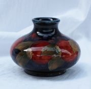 A Moorcroft pottery vase of squat circular form with a dark blue ground decorated in the