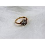 A seven stone diamond ring set with old cut stones in the form of a daisy to a rubbed over white