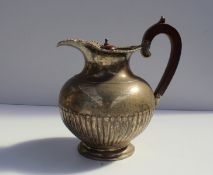 A silver hot water pot with a scrolling and leaf rim above a half rimmed body on a spreading foot,