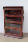 A mahogany sectional bookcase with a moulded top above four up and over glazed door on a plinth