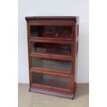 A mahogany sectional bookcase with a moulded top above four up and over glazed door on a plinth
