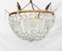 A lustre drop ceiling lamp shade, with cascading lustres attached to a gilt metal leaf moulded ring,