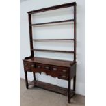 An 18th century South Wales oak dresser the rack with a moulded cornice and open back, the base with
