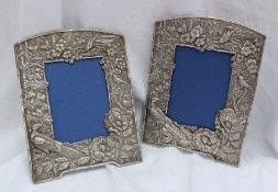 A pair of Oriental white metal photograph frames decorated with bamboo, large flowerheads and birds,