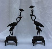 A pair of Japanese bronze candlesticks in the form of cranes and young cranes on a rectangular base