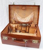 A George V leather suitcase partially fitted with silver and glass dressing table items including
